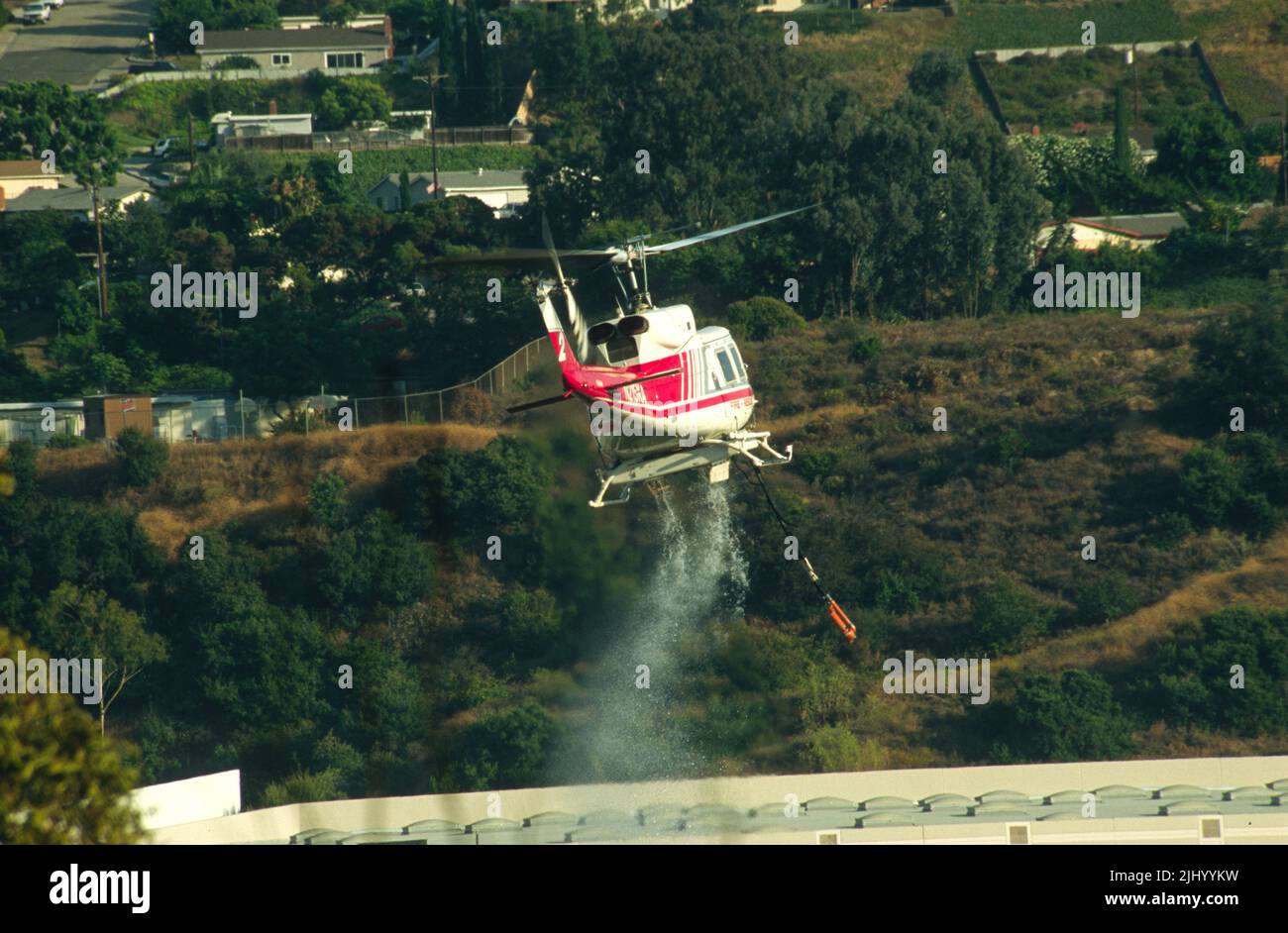 San Diego Regional Fire-Rescue Hubschrauber von Kachina Aviation macht einen Wassertropfen auf einem funktionierenden Wildland (Pinsel) Feuer. Stockfoto
