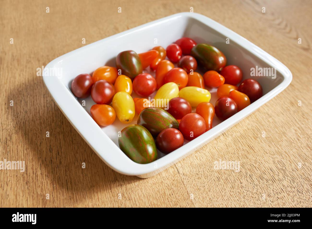 Essen. Nahaufnahme von roma- oder Kirschtomaten in einer Glasschüssel, serviert auf einem Holztisch für Ernährung, gesunde Salate und Ernährung. Frisches, biologisches Obst Stockfoto