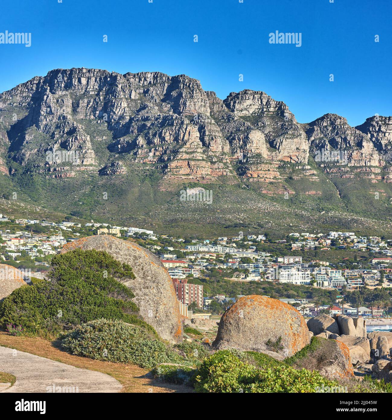 Landschaftlich schöner Blick auf die 12 Apostles Bergkette mit Blick auf die nahe gelegenen Häuser im Vorort Camps Bay, Kapstadt.. Landschaft mit entspannender landschaftlicher Aussicht mit Felsen Stockfoto