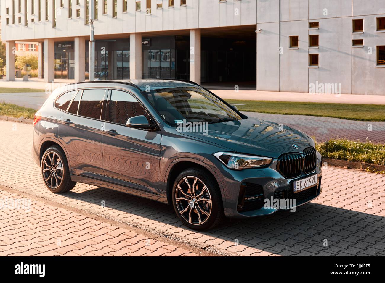 BMW X1 25e, Hybrid, Plug-in-Auto, geparkt neben einem modernen Gebäude. Die Gesamtleistung beider Motoren beträgt 220HP. Elektrische Reichweite bis zu 52 km Katowice/Polan Stockfoto