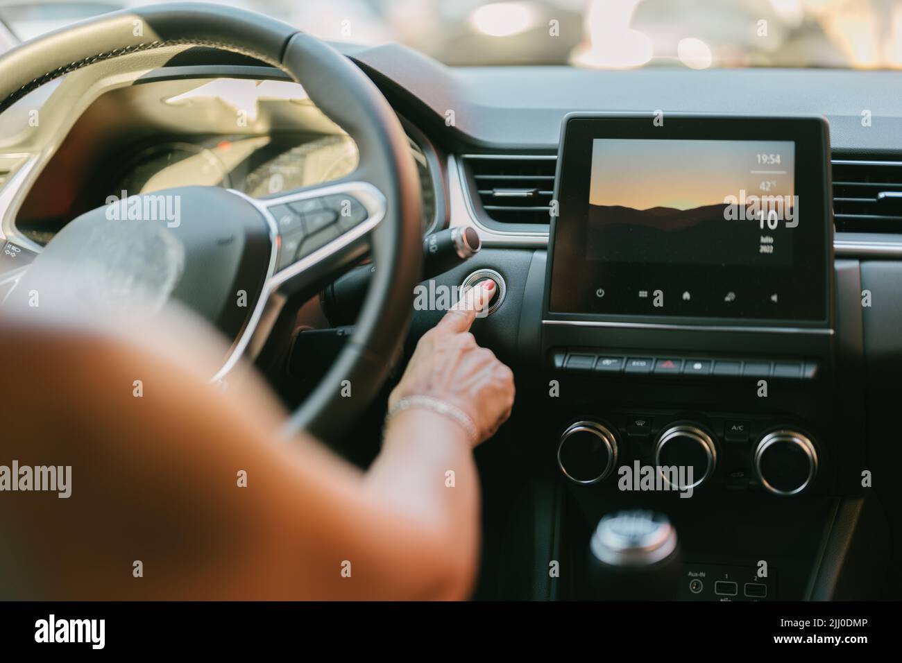 Frau, die den automatischen Start-Knopf an ihrem Auto drückt Stockfoto