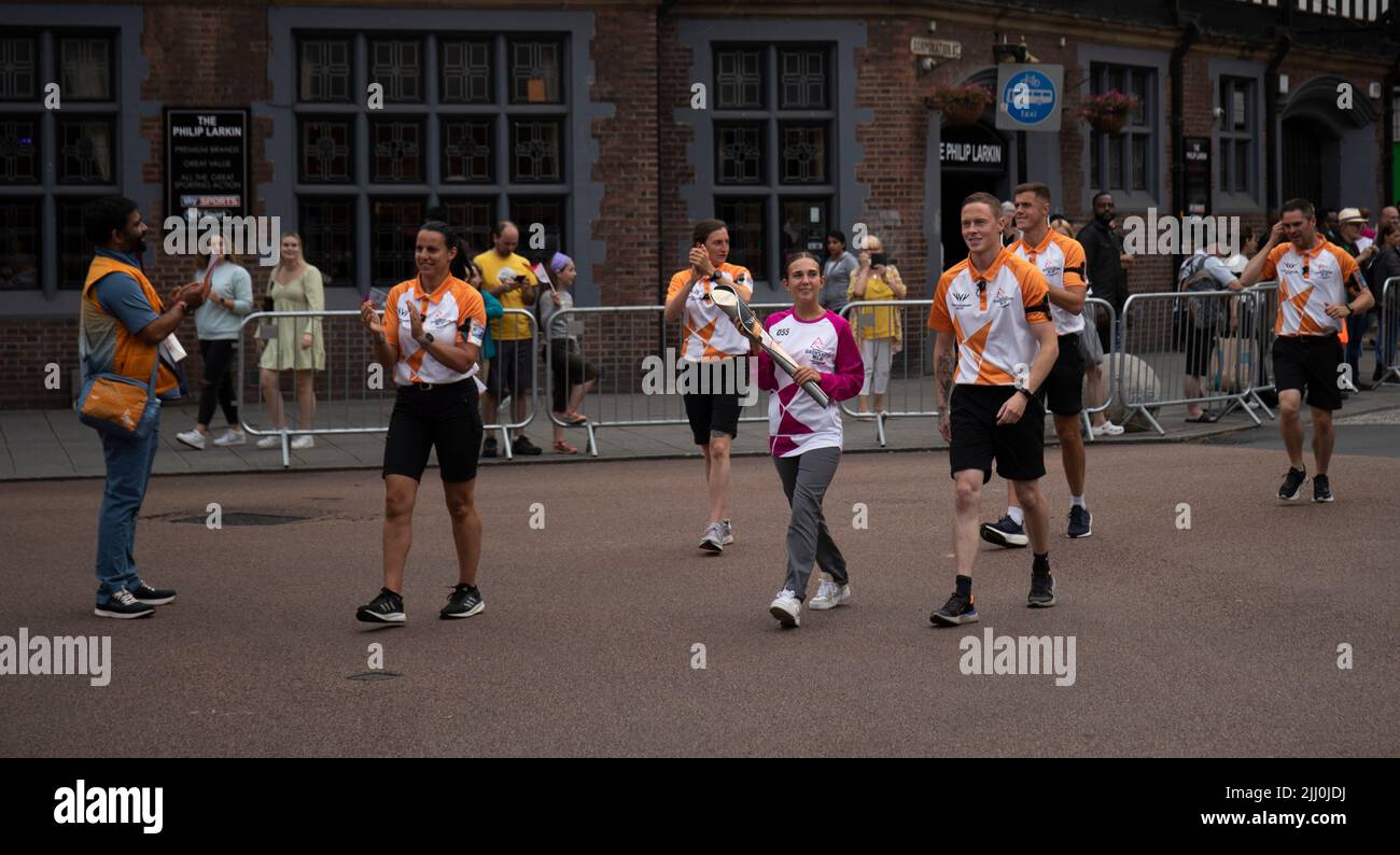 Ein Baton-Träger trägt das Baton der Commonwealth Games Queen durch das Zentrum von Coventry. Stockfoto