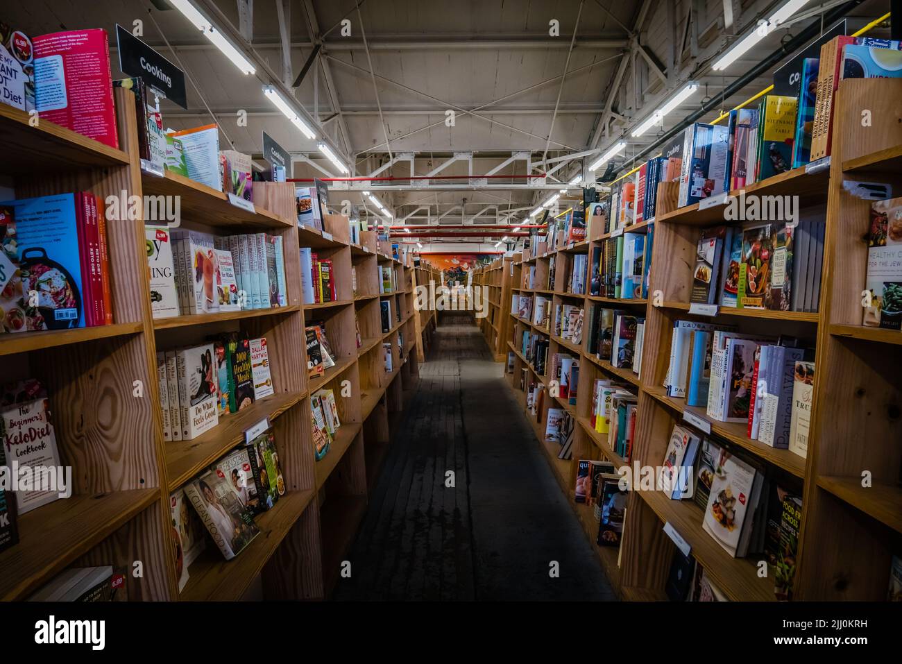 Kurze Bücherregale auf beiden Seiten eines Gangs in einem unmöblierten Buchladen Stockfoto