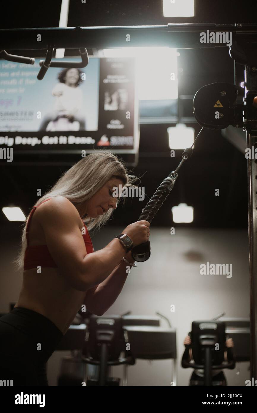 Blonde Frau beim Training im Fitnessstudio, die Sonne kommt durch das Fenster Stockfoto