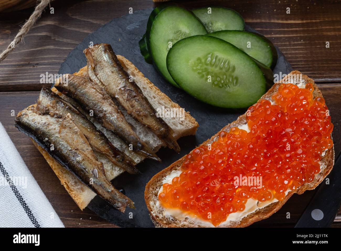 Nahaufnahme russischer Snack Lachskaviar, Sprotte Baltic. Low-Key, selektiver Fokus, Stillleben. Konzept der spät-Nacht-Essen, kleine Mitternachtssnack, Midnight Stockfoto