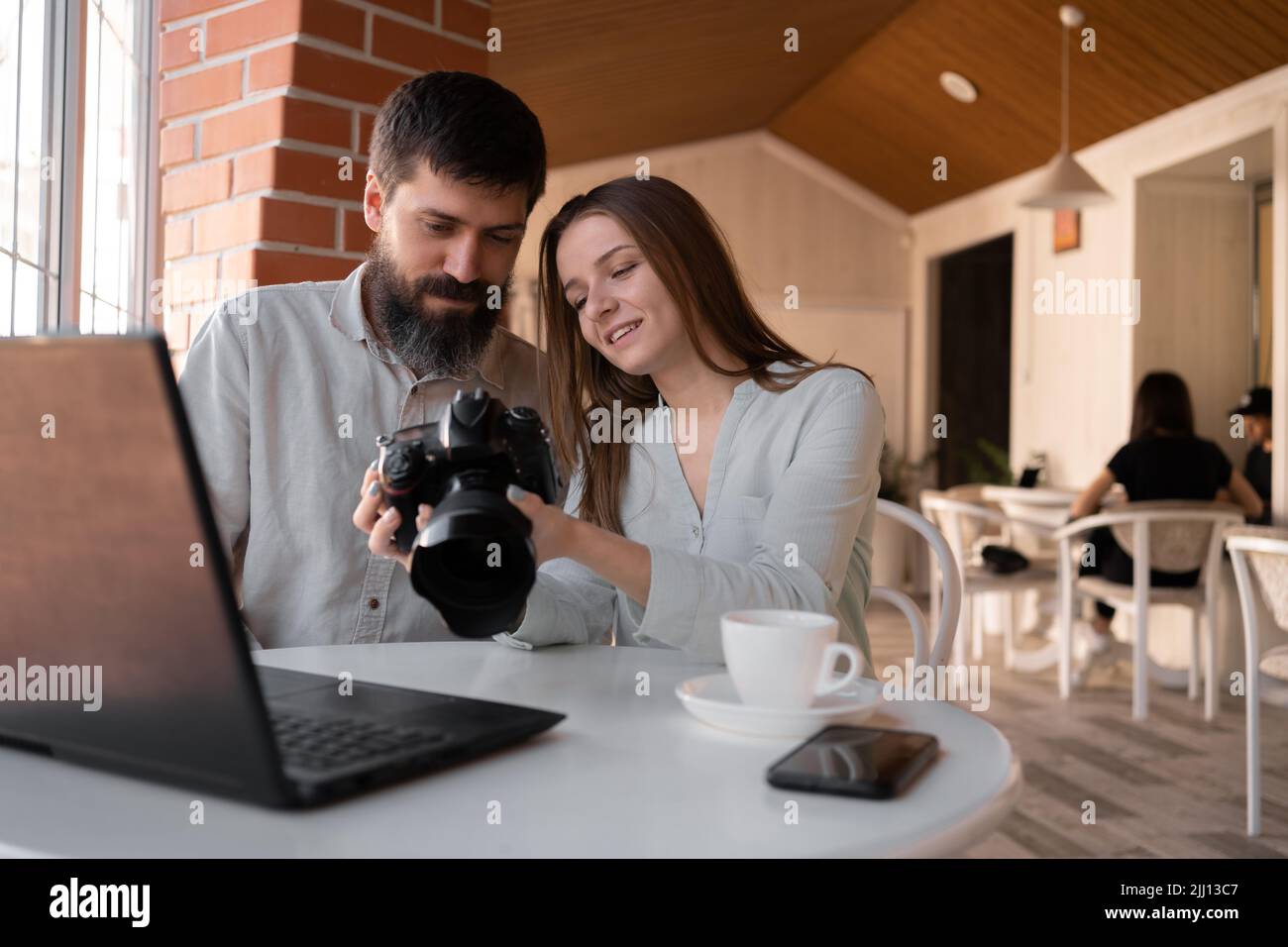 Kollegen Fotografen, die im Café mit Kamera und Laptop arbeiten und Bilder vor der Kamera ansehen. Neues Konzept moderner Technologien Stockfoto