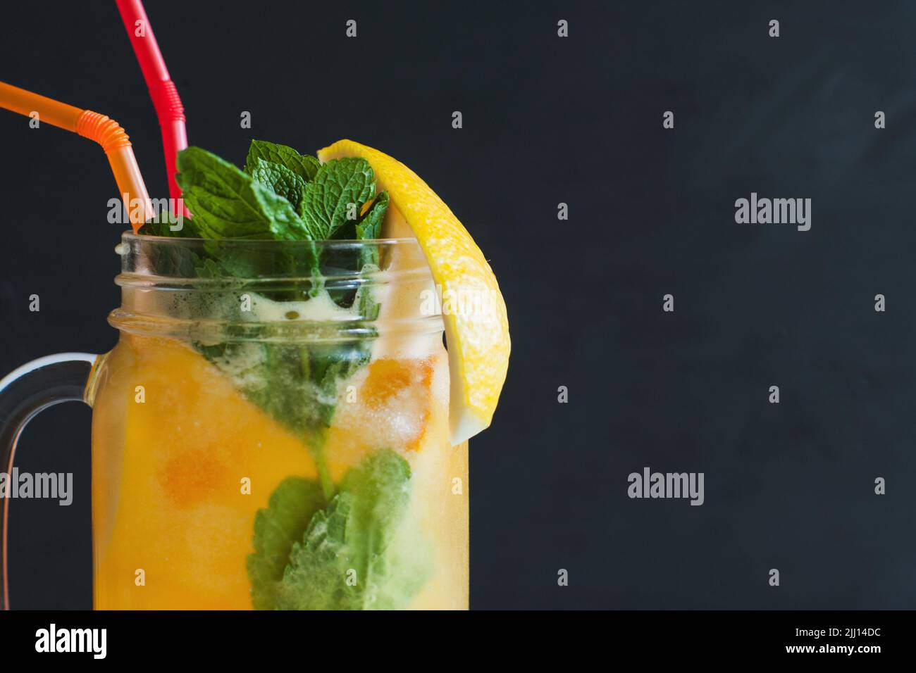 Orangefarbener Cocktail im Glas auf schwarzem Hintergrund Stockfoto