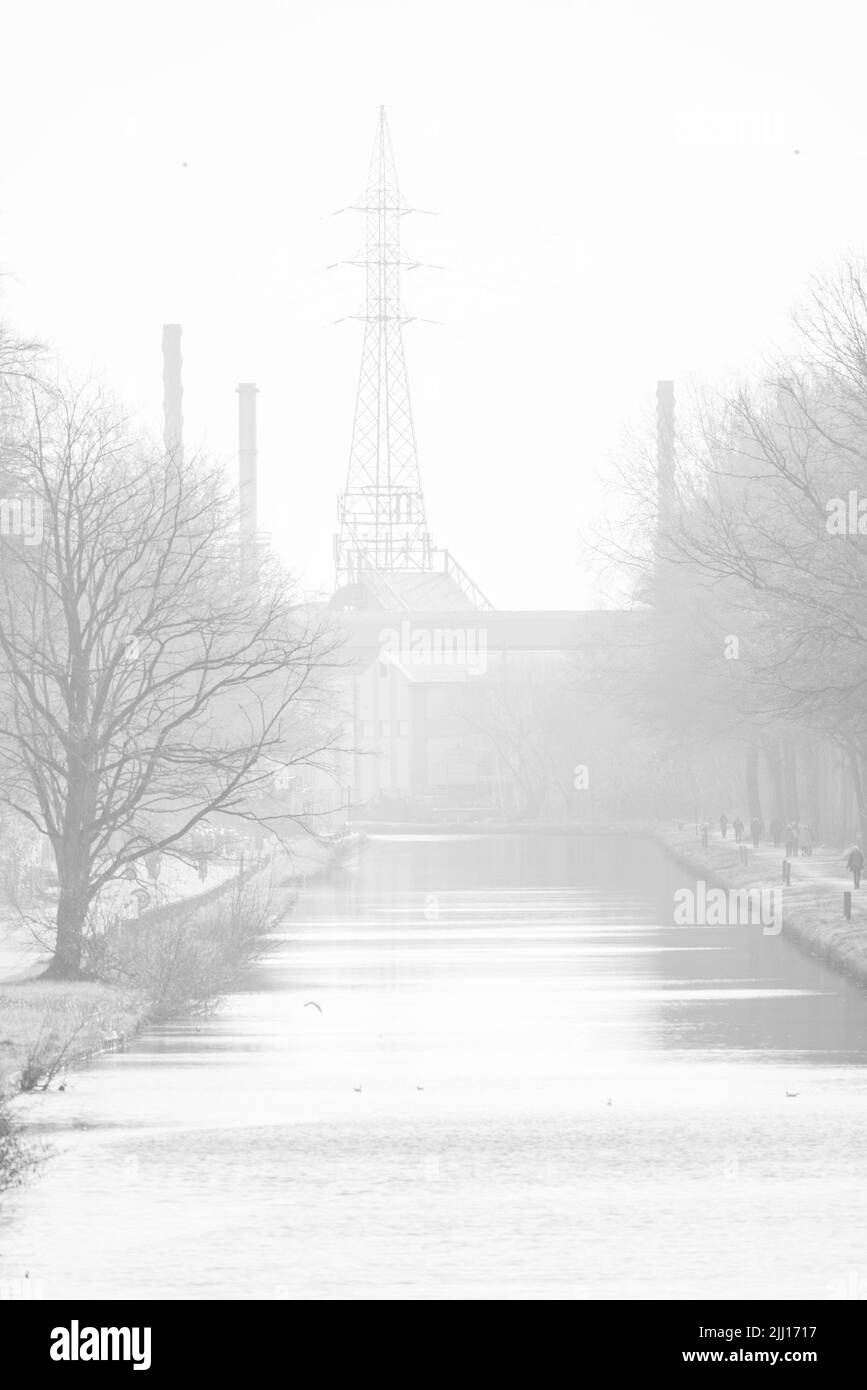 High Key Schwarz-weiße Industrielandschaft mit Stromleitungen, Bäumen, Straße und einem Kanal oder einer Wasserstraße. Hochwertige Fotos Stockfoto