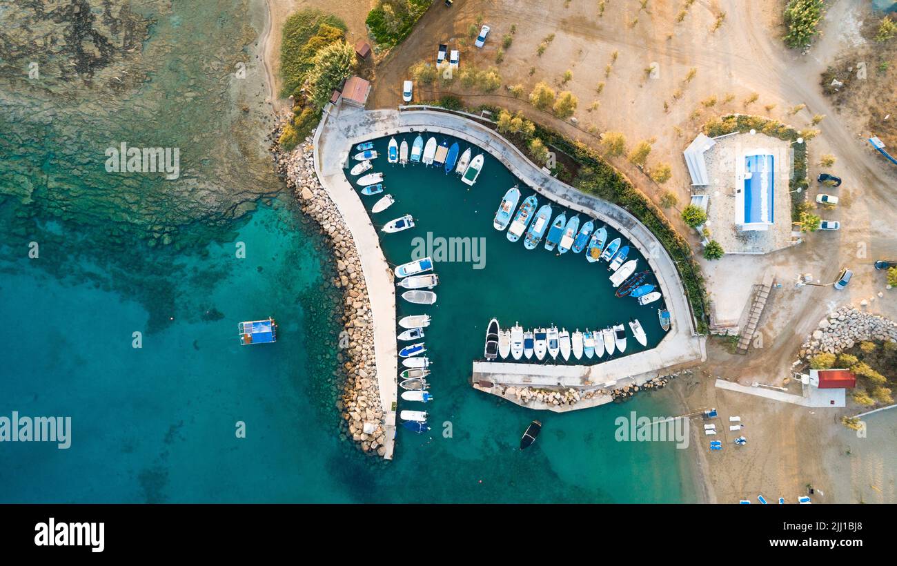 Luftbild des Sonnenuntergangs an der Küste und die weiße, gewaschene Kapelle am Strand Agia Triada, Protaras, Famagusta, Zypern von oben. Vogelperspektive auf Tour Stockfoto