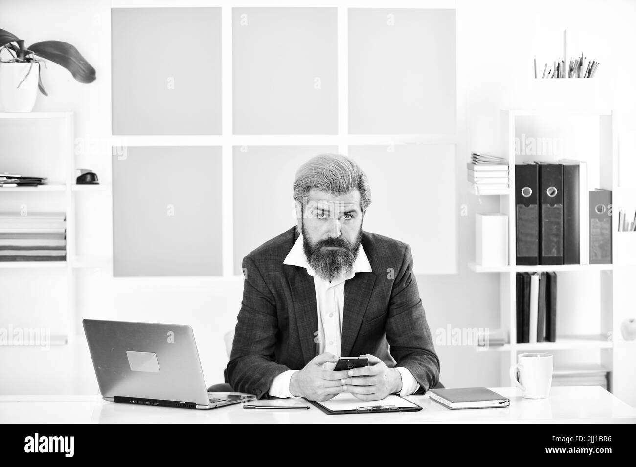 Bärtiger Mann in Jacke mit Laptop. Chef am Arbeitsplatz. Modernes Büroleben. Fernarbeit während Coronavirus Quarantäne. Reife Schullehrer. Business Stockfoto
