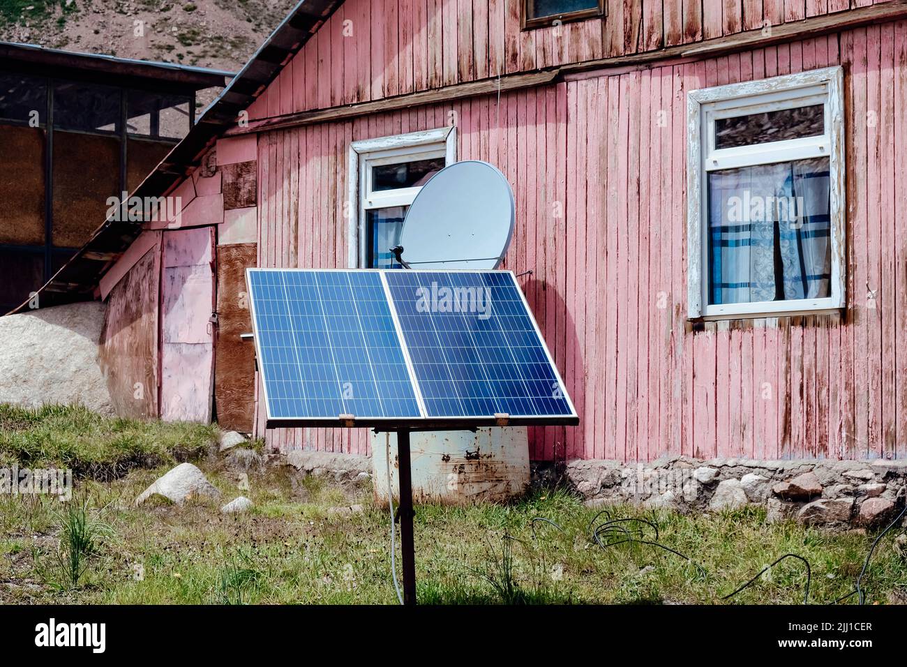 Kleines Solarpanel in der Nähe des alten Holzhauses. Stockfoto