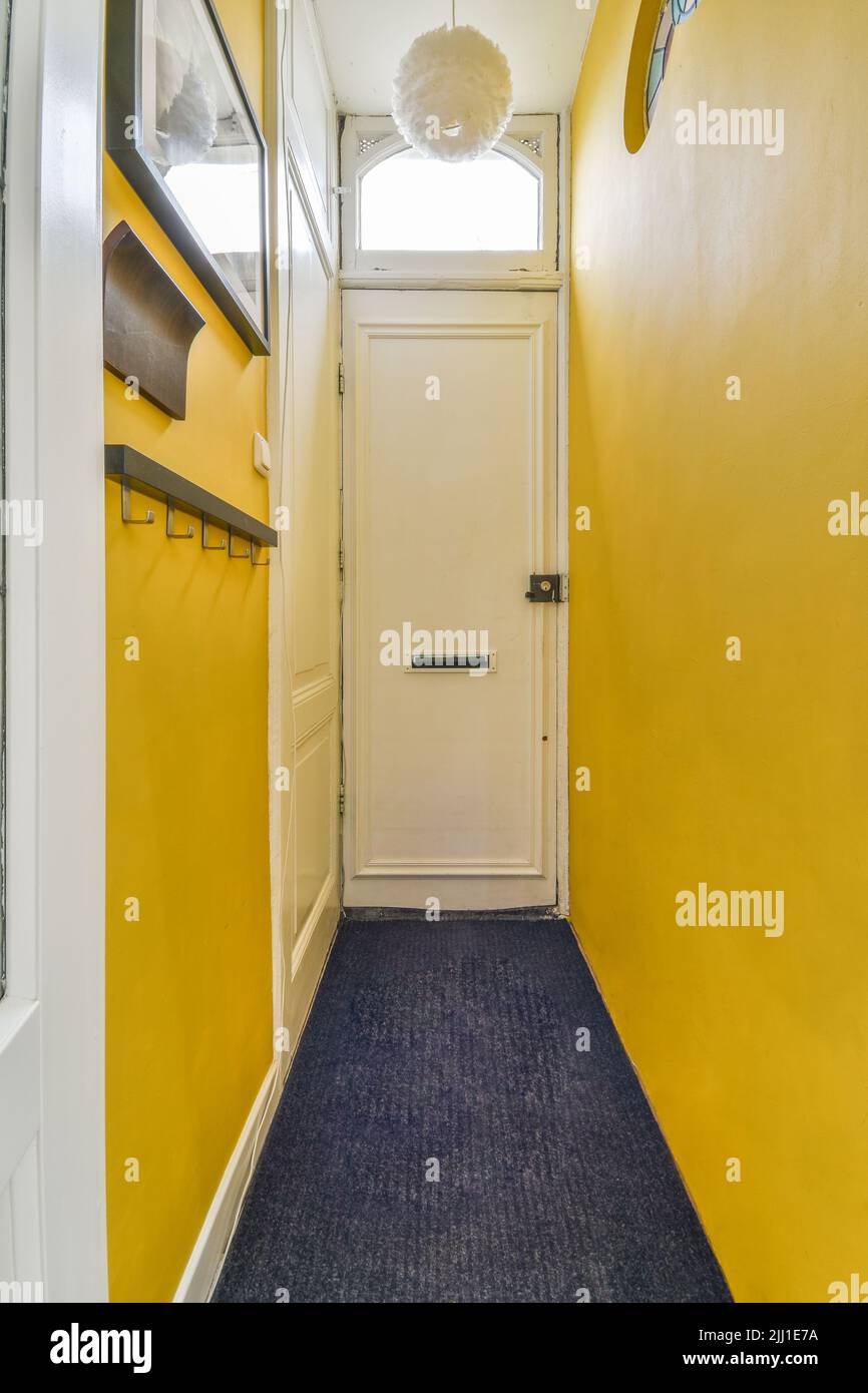 Heller, enger Flur mit vielen Türen in gelben Wänden und glühender Lampe über dem Holzfußboden Stockfoto