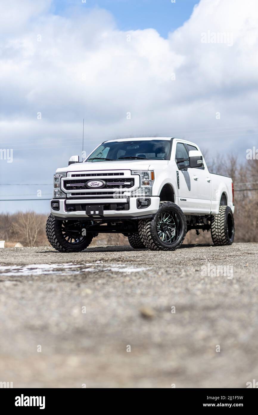 Eine vertikale Aufnahme eines weißen, angehobenen Ford-Lkw mit Aftermarket-Rädern in Oswego, New York Stockfoto