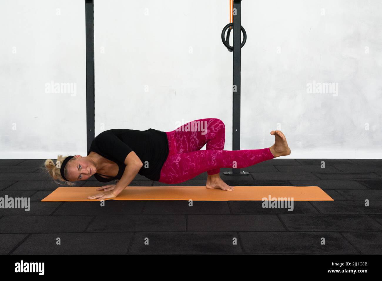 Junge blonde Frau Durchführung utthita parshwa chatuspadasana, Armausgleich Yoga-Pose trägt bunte rosa Yoga Leggings. Stockfoto