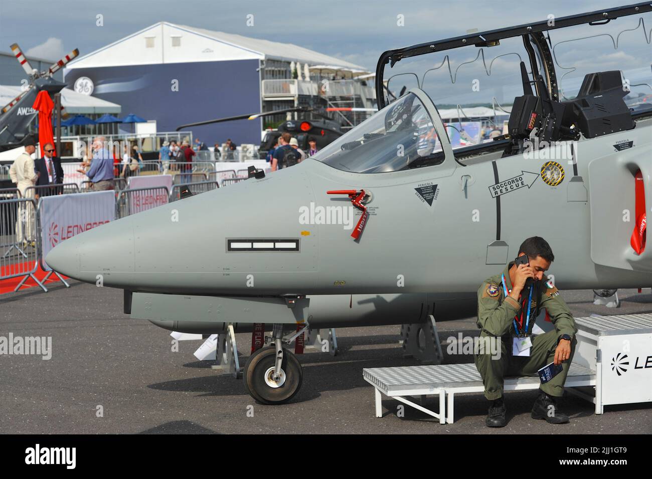 Ein Testpilot, der sich neben seinem Flugzeug entspannt, ein Aermacchi M-345 Dual-Role Jet Trainer am fünften Tag der Farnborough International Airshow (FIA), die in Farnborough, Hampshire, Großbritannien, stattfindet. Die Air Show, eine alle zwei Jahre stattfindende Messe für die Luftfahrtindustrie, ist die größte ihrer Art und zieht zivile und militärische Einkäufer aus der ganzen Welt an. Fachbesucher sind in der Regel über 100.000 Besucher. Auf die Handelsseite der Messe folgt ein Wochenende mit Flugdisplays, die an die breite Öffentlichkeit gerichtet sind. Auf der Messe wird viel getan, und auf der letzten Messe im Jahr 2018 waren es 192 Milliarden US-Dollar im Wert von o C Stockfoto