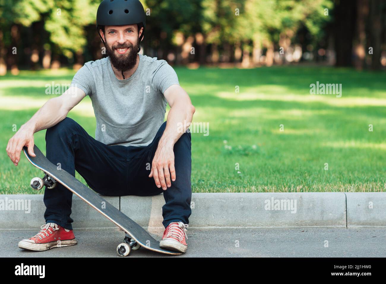 Gut gelaunter Skateboarder hat eine kurze Pause Stockfoto