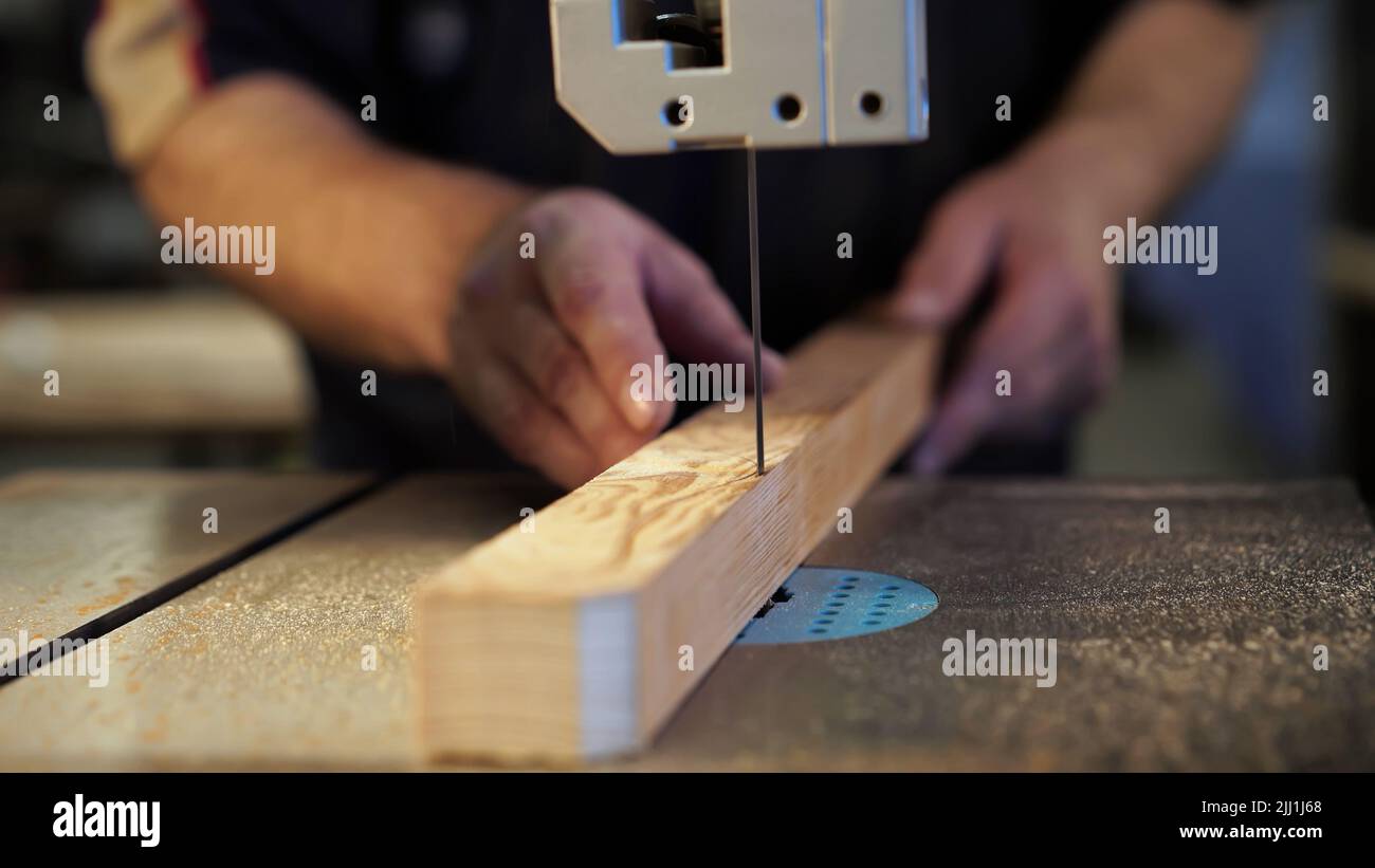 Handarbeit, Tischlerei Konzept, Holzbearbeitung. Zimmermann, der in einem Fabrikatelist arbeitet. Tischler schneidet Holzbrett auf Stichsägemaschine. Stockfoto