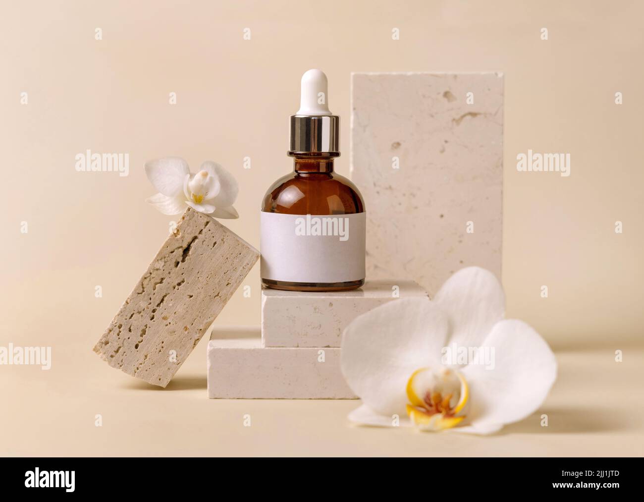 Braune Glasflasche auf Stein bei weißen Orchideenblüten auf hellgelber Nahaufnahme, Etikett Mockup. Hautpflege handgemachtes Beauty-Produkt, Serum oder lotio Stockfoto