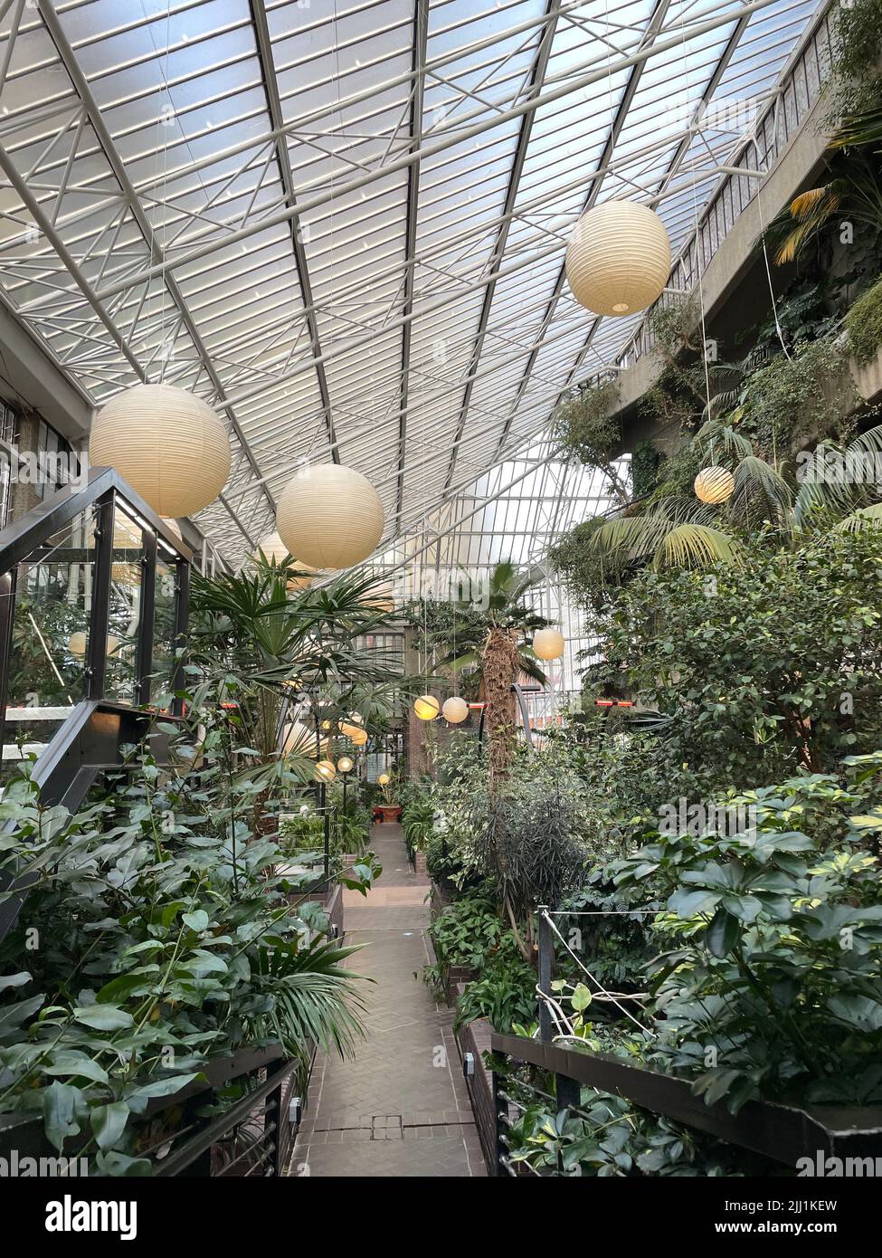 Eine vertikale Aufnahme einer runden Laterne, die über einem Brunnen mit Pflanzen in einem botanischen Garten hängt Stockfoto