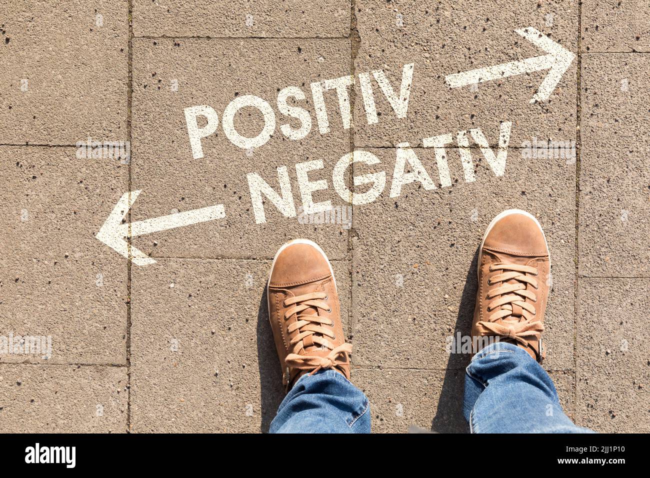 Ein brauner Schuh mit Text, der die Richtung zu positiv oder negativ auf einem Boden zeigt Stockfoto