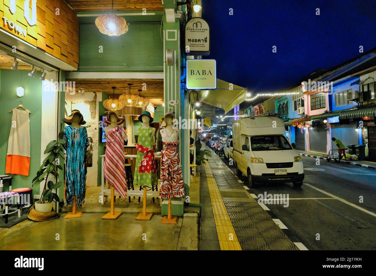 Die Abenddämmerung fällt an der Thalang Road in der Altstadt von Phuket Town, Thailand; links: Eine der modischen kleinen Boutiquen, die ihre Waren zeigen Stockfoto