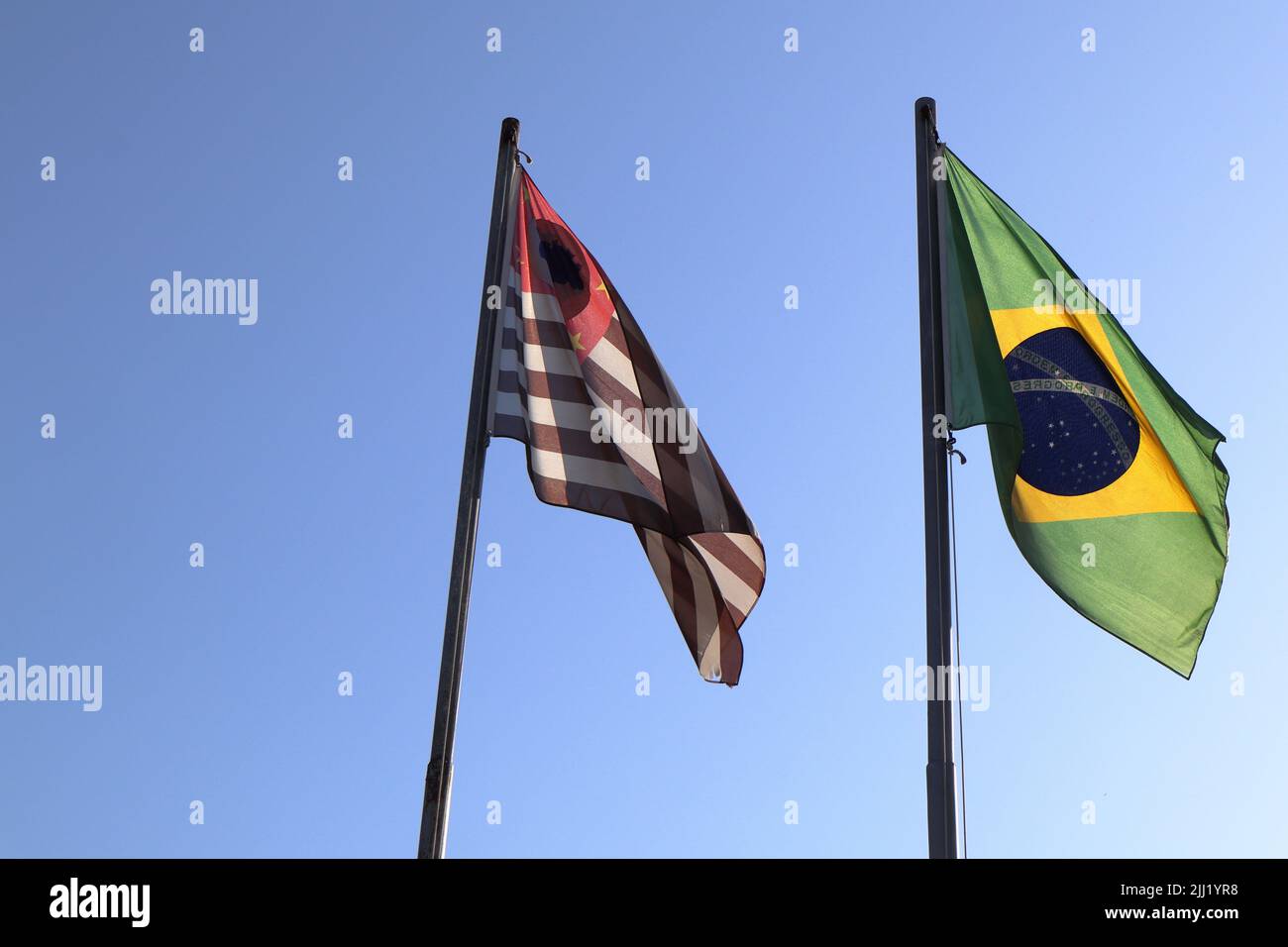 Schwenken Sie farbenfrohe Fahnen von Sao Paulo und Brasilien gegen den blauen Himmel. Stockfoto