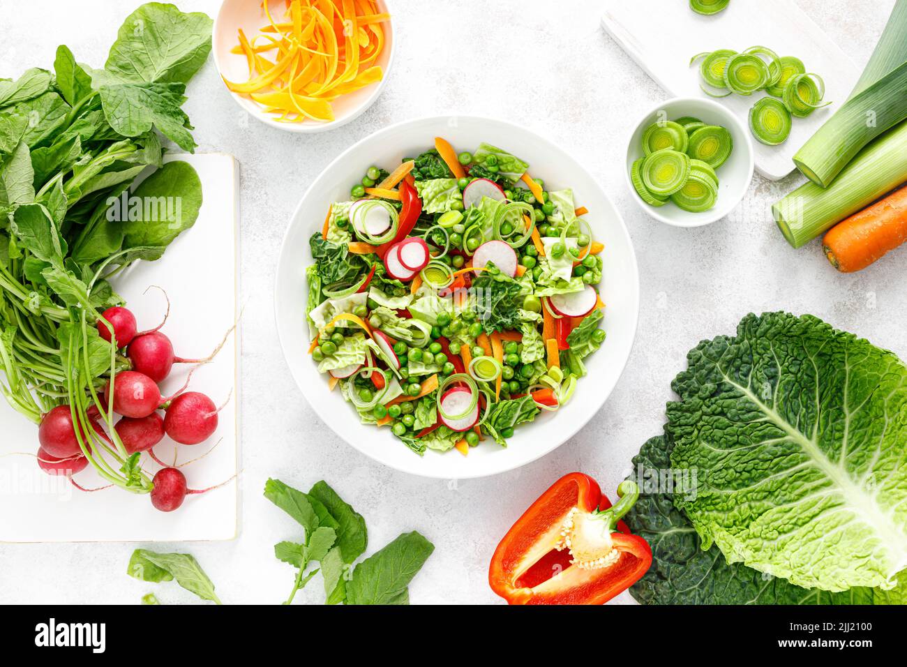 Frischer vegetarischer grüner Salat mit savoy-Kohl, roher Karotte, Rettich, Paprika, Lauch und grünen Erbsen Stockfoto