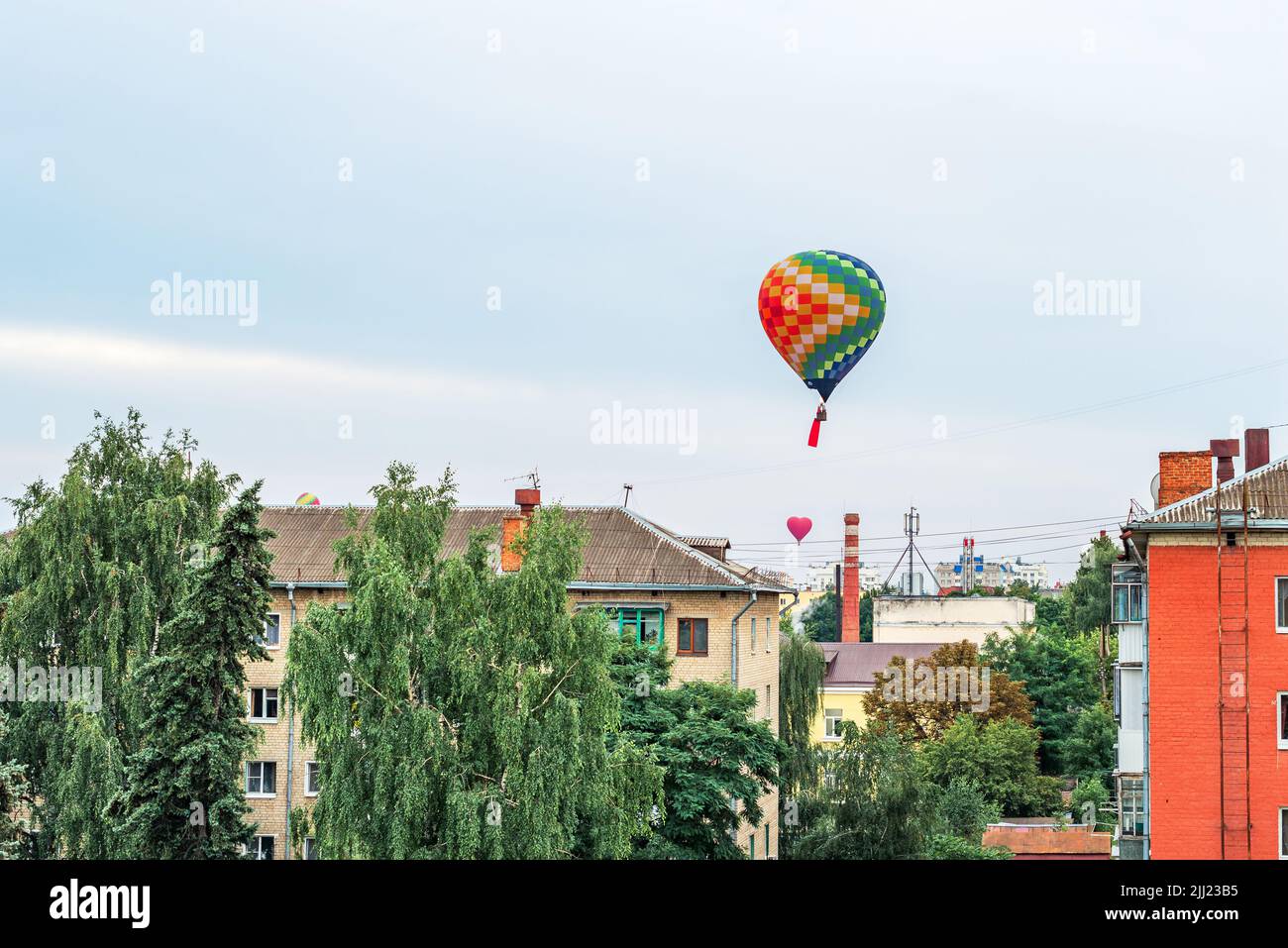 Bunte Luftballons fliegen am Himmel über den Dächern von Hochhäusern in einer Provinzstadt Stockfoto Bunte Luftballons fliegen am Himmel über den Dächern von Hochhäusern in einer Provinzstadt Stockfoto