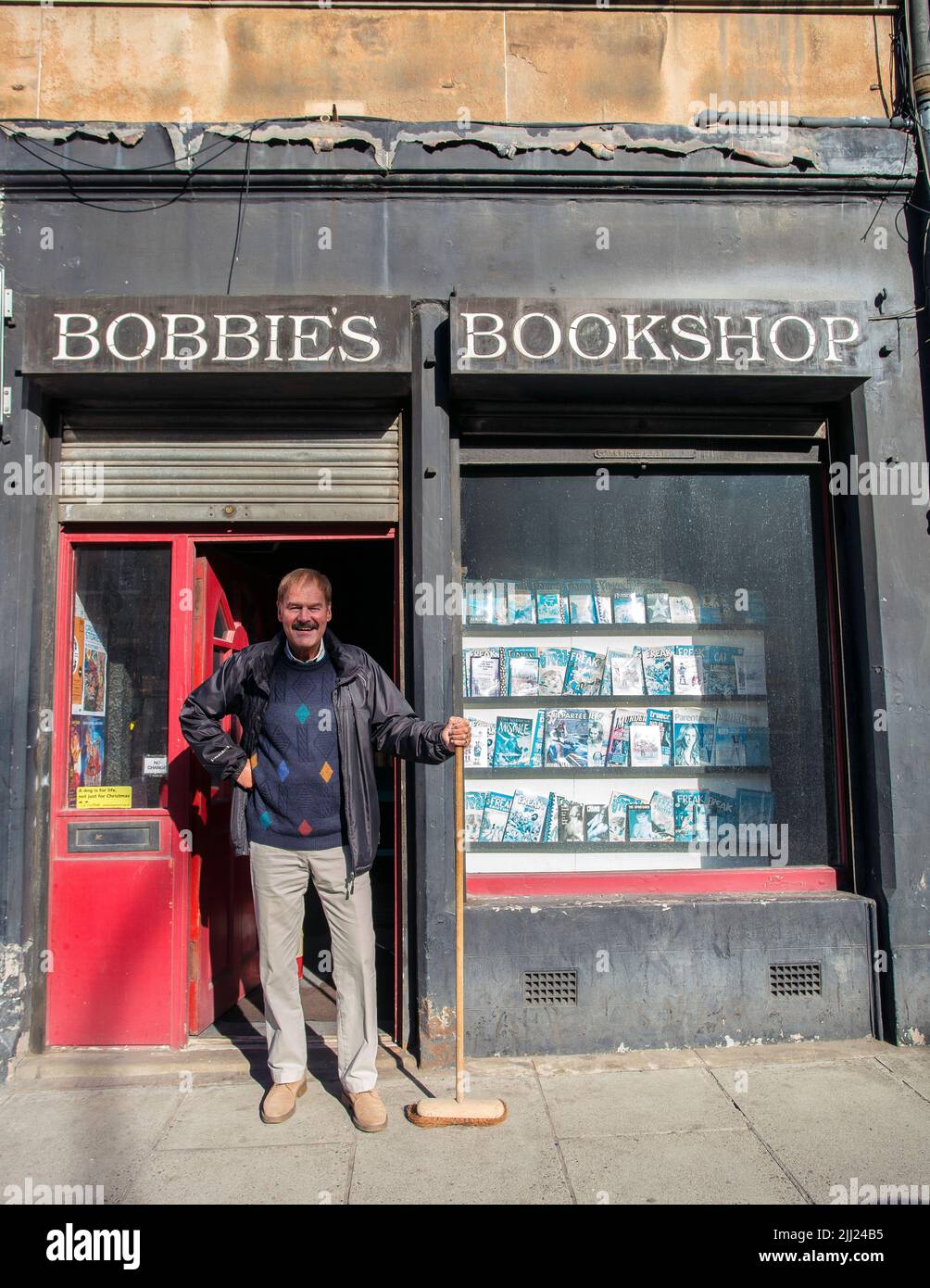 Buchhändler steht mit Besen vor der Buchhandlung Stockfoto