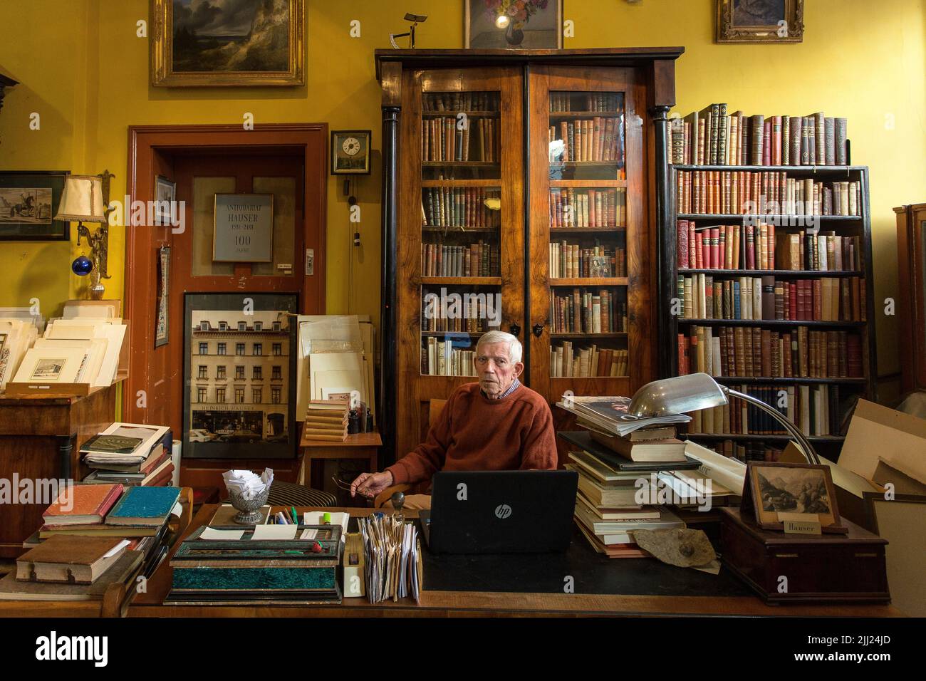 Reifer Mann sitzt in antiquarian Buchhandlung. Stockfoto