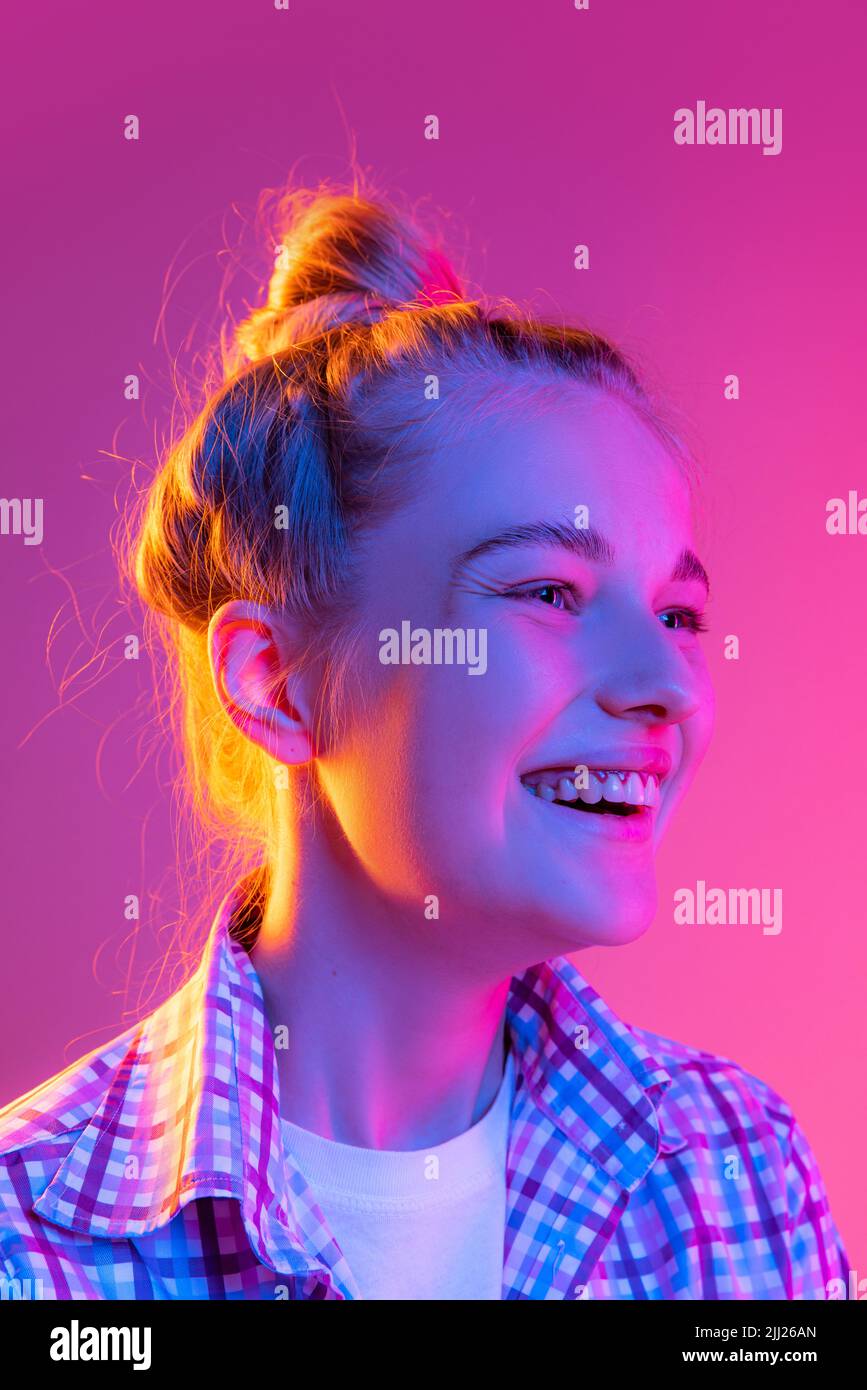 Porträt von entzückenden jungen Mädchen, Student mit Tragen karierten Shirt isoliert auf magenta Farbe Hintergrund in Neonlicht. Konzept von Schönheit, Kunst, Mode Stockfoto