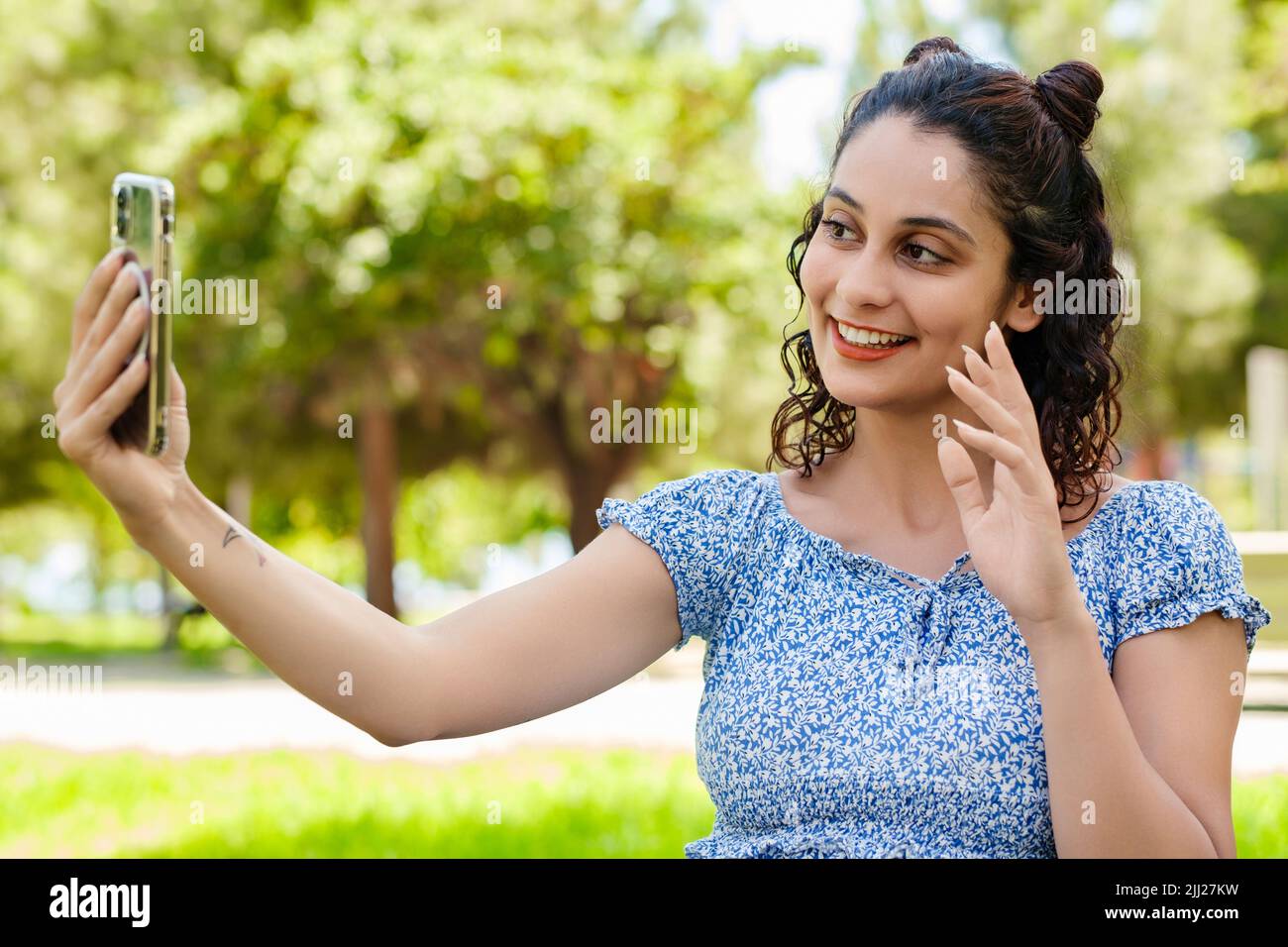 Junge Brünette Mädchen lächelnd glücklich tragen Sommerkleid im Stadtpark, im Freien tun Videoanruf oder Selfie mit dem Smartphone. Stockfoto