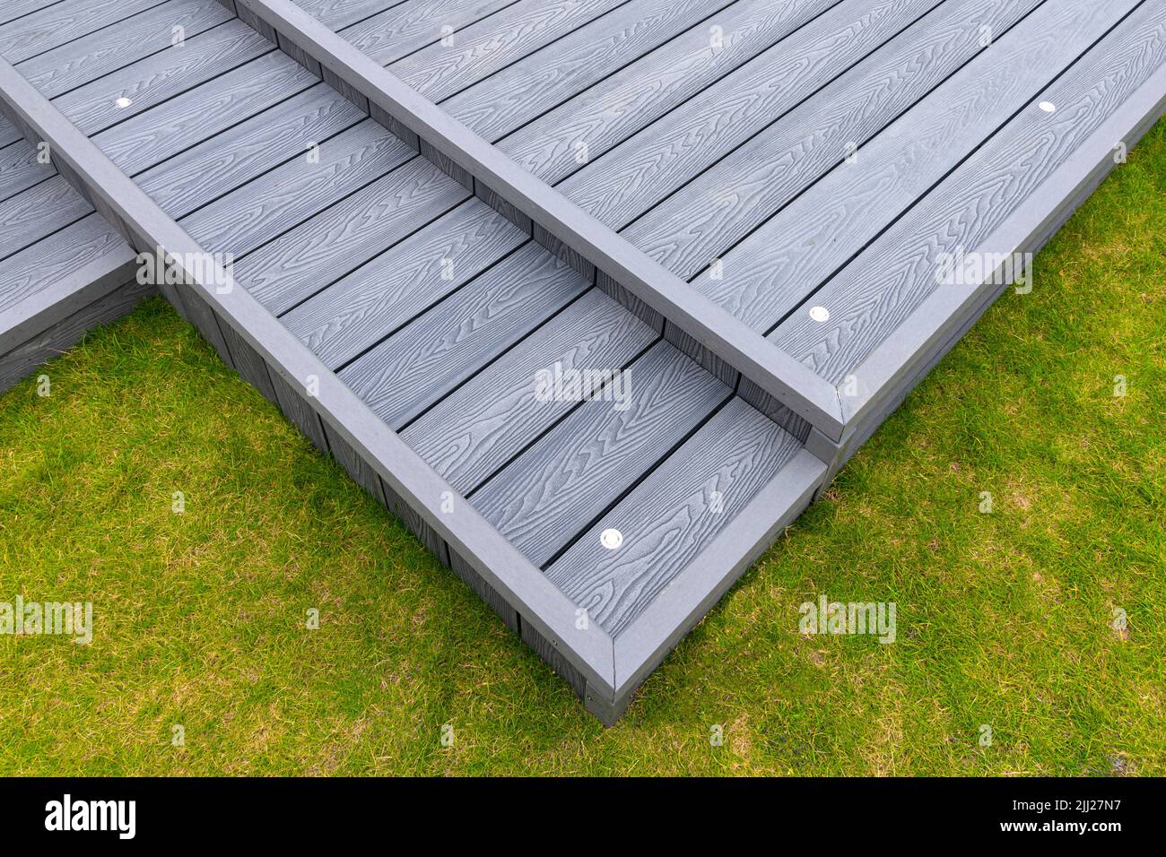 Aschgraue Verbundterrassen, die auf zwei Ebenen in einem Wohngarten mit Niederspannungs-Deckelbeleuchtung errichtet wurden. Gutes Bild für eine Landschaft Stockfoto