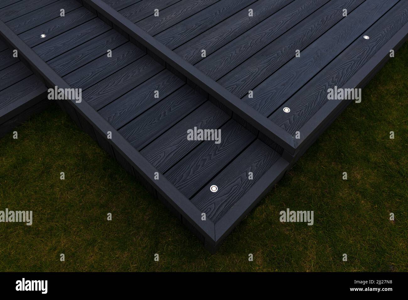 Aschgraue Verbundterrassen, die auf zwei Ebenen in einem Wohngarten mit Niederspannungs-Deckelbeleuchtung errichtet wurden. Gutes Bild für eine Landschaft Stockfoto