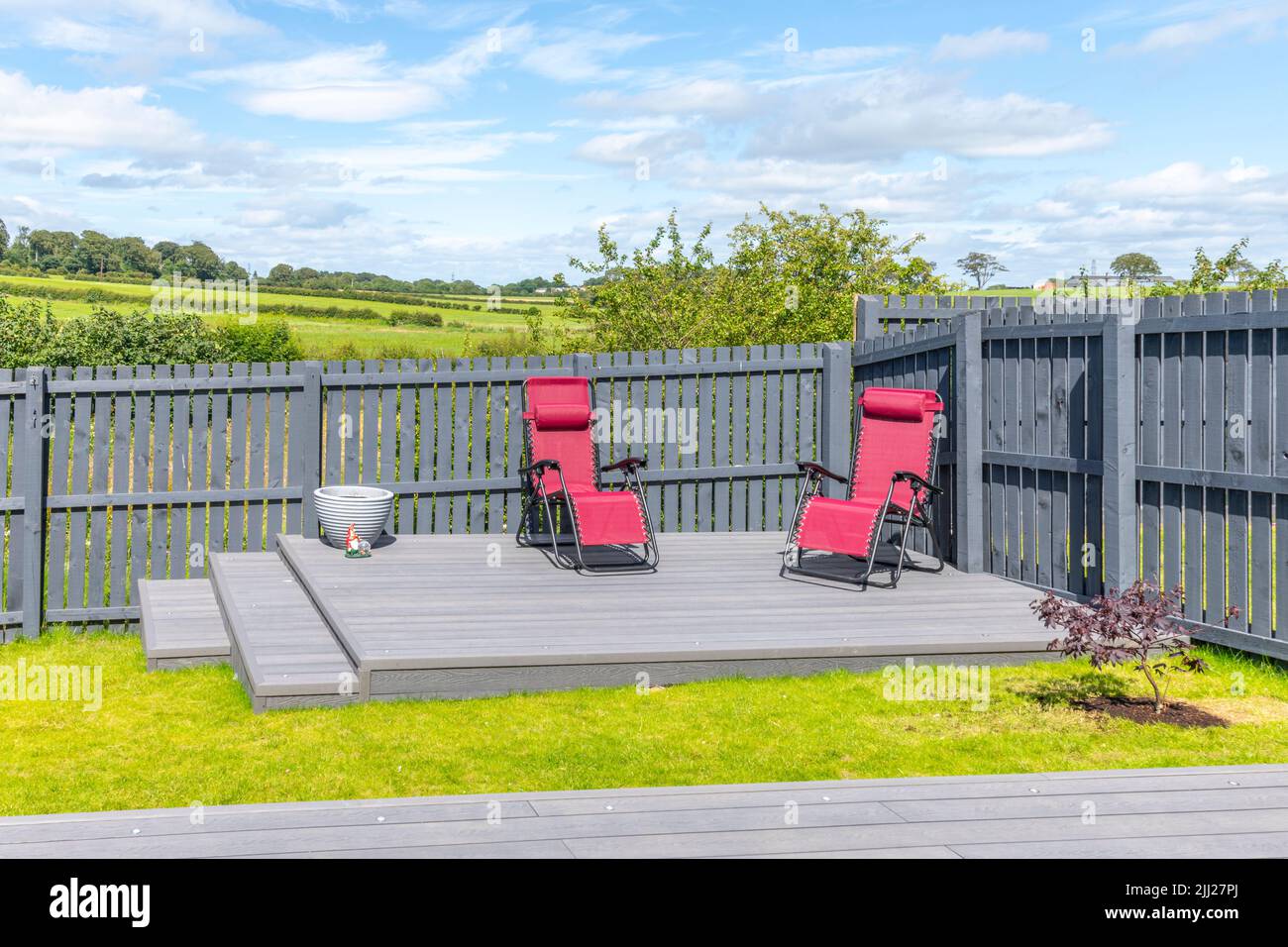 Aschgraue Verbundterrassen, die auf zwei Ebenen in einem Wohngarten mit Niederspannungs-Deckelbeleuchtung errichtet wurden. Gutes Bild für eine Landschaft Stockfoto