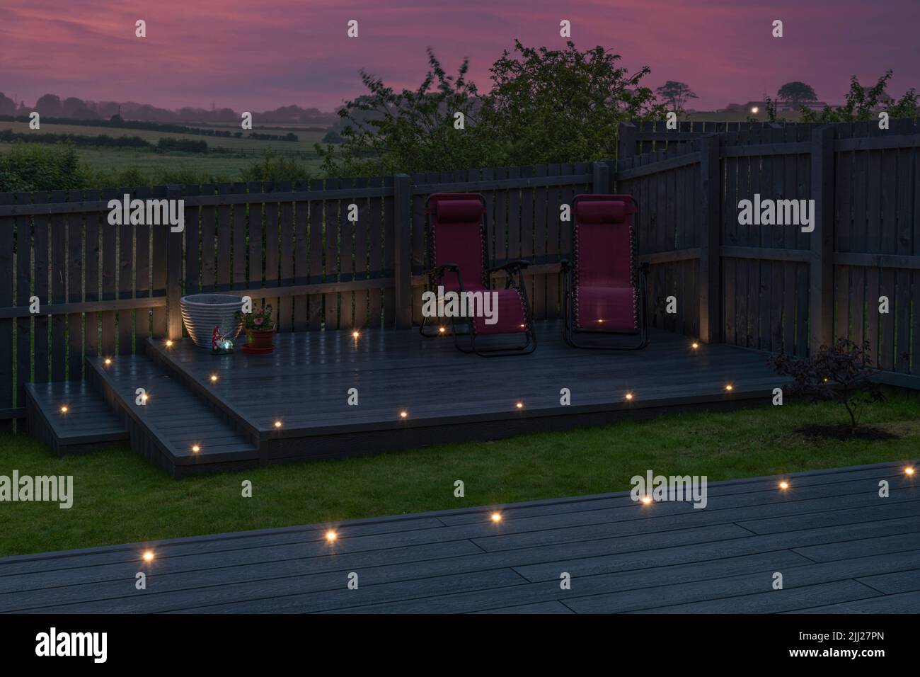 Aschgraue Verbundterrassen, die auf zwei Ebenen in einem Wohngarten mit Niederspannungs-Deckelbeleuchtung errichtet wurden. Gutes Bild für eine Landschaft Stockfoto