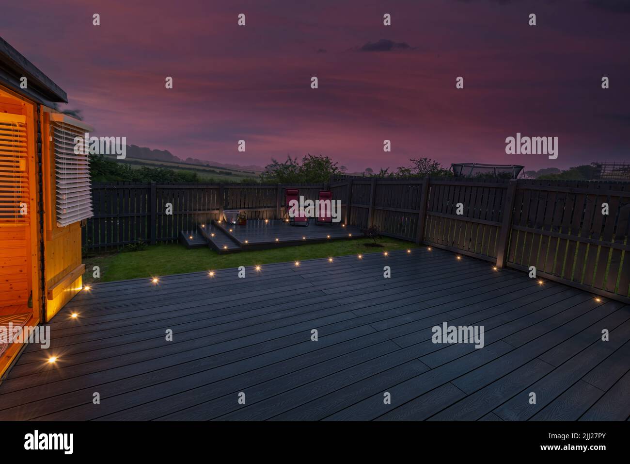 Aschgraue Verbundterrassen, die auf zwei Ebenen in einem Wohngarten mit Niederspannungs-Deckelbeleuchtung errichtet wurden. Gutes Bild für eine Landschaft Stockfoto