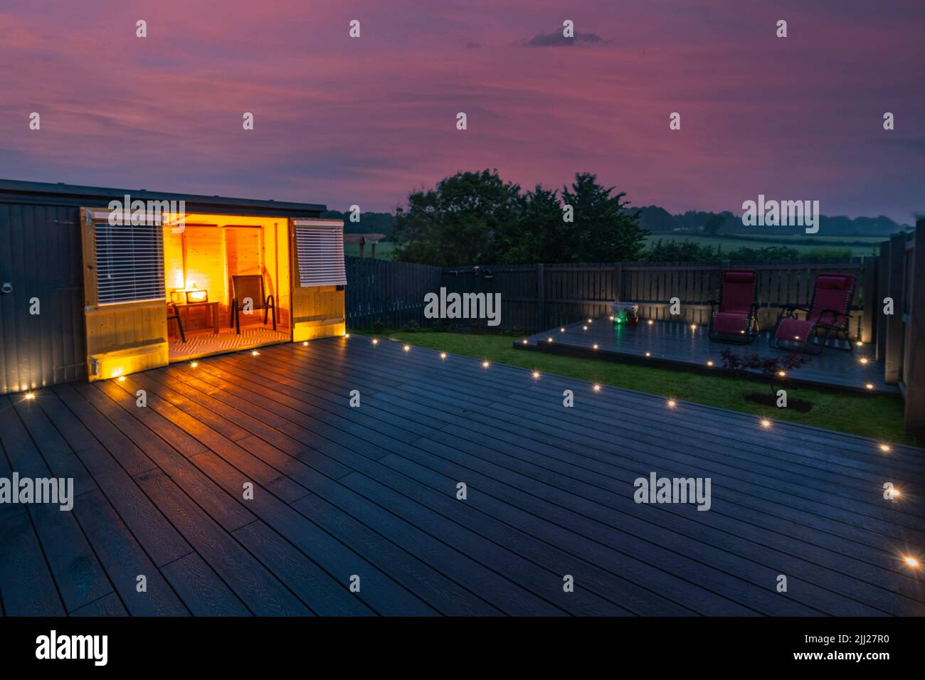 Aschgraue Verbundterrassen, die auf zwei Ebenen in einem Wohngarten mit Niederspannungs-Deckelbeleuchtung errichtet wurden. Gutes Bild für eine Landschaft Stockfoto