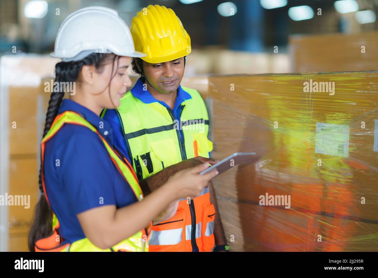 Asiatische Lagerarbeiter, die den Versandstatus auf einem digitalen Tablet-Computer überprüfen, bereiten sich auf die Auslieferung an den Kunden vor. Teamarbeit der Mitarbeiter. Stockfoto