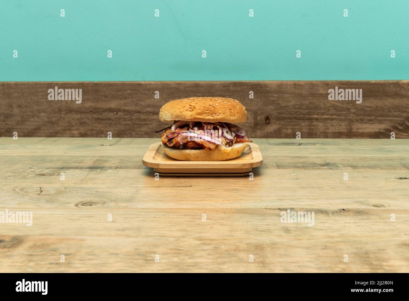 Burger mit gegrilltem Fleisch und rohen roten Zwiebeln auf Holztisch Stockfoto