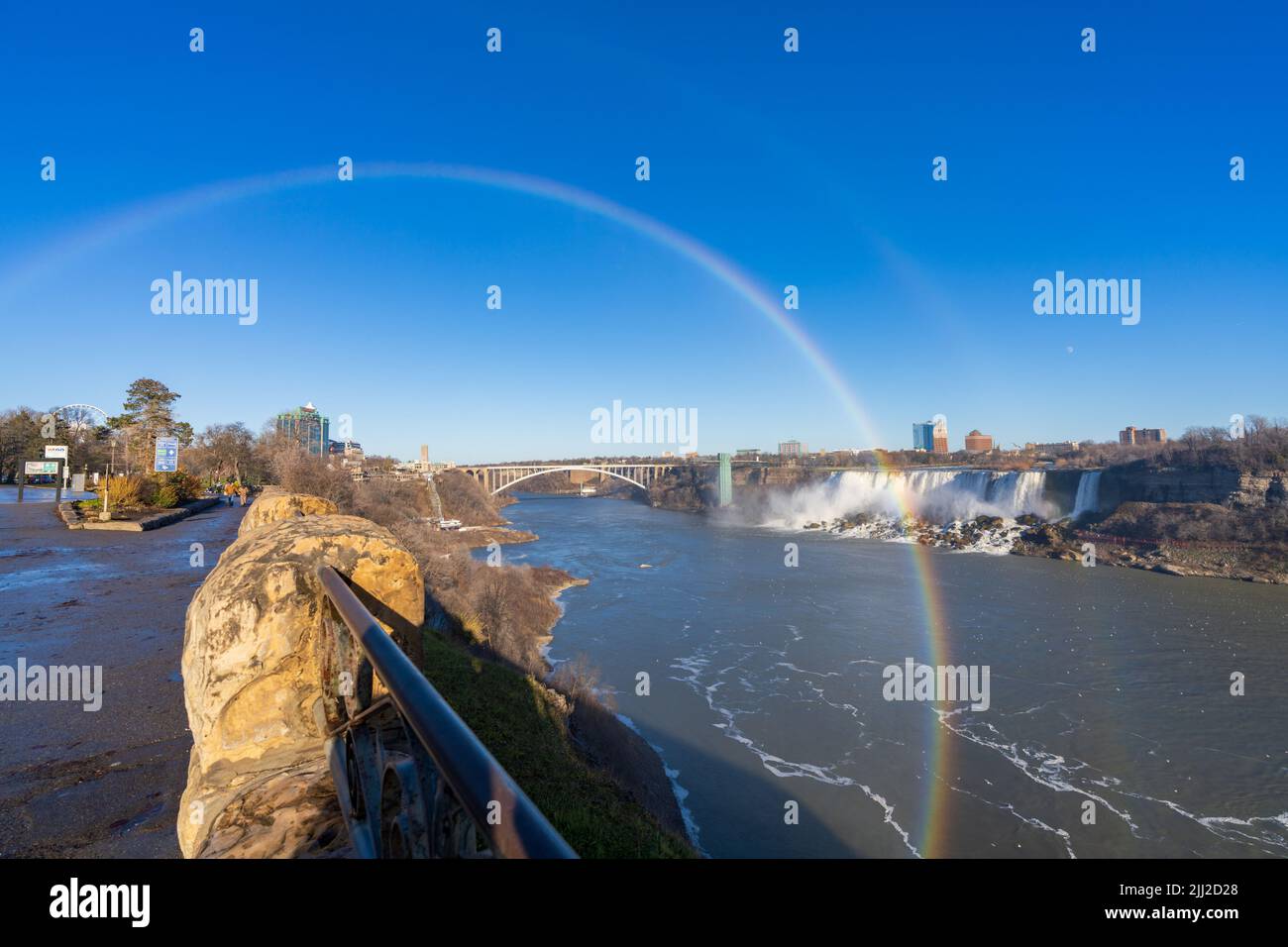 Niagara Falls, Ontario, Kanada - Dezember 13 2021 : Fallsview Trail an einem sonnigen Tag mit doppeltem Regenbogen. American Falls im Hintergrund. Stockfoto