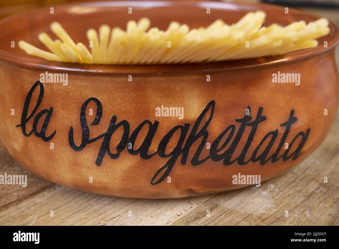 Steingutpfanne mit rohen Spaghetti innen und dem Wort Spaghetti auf einer Seite Stockfoto