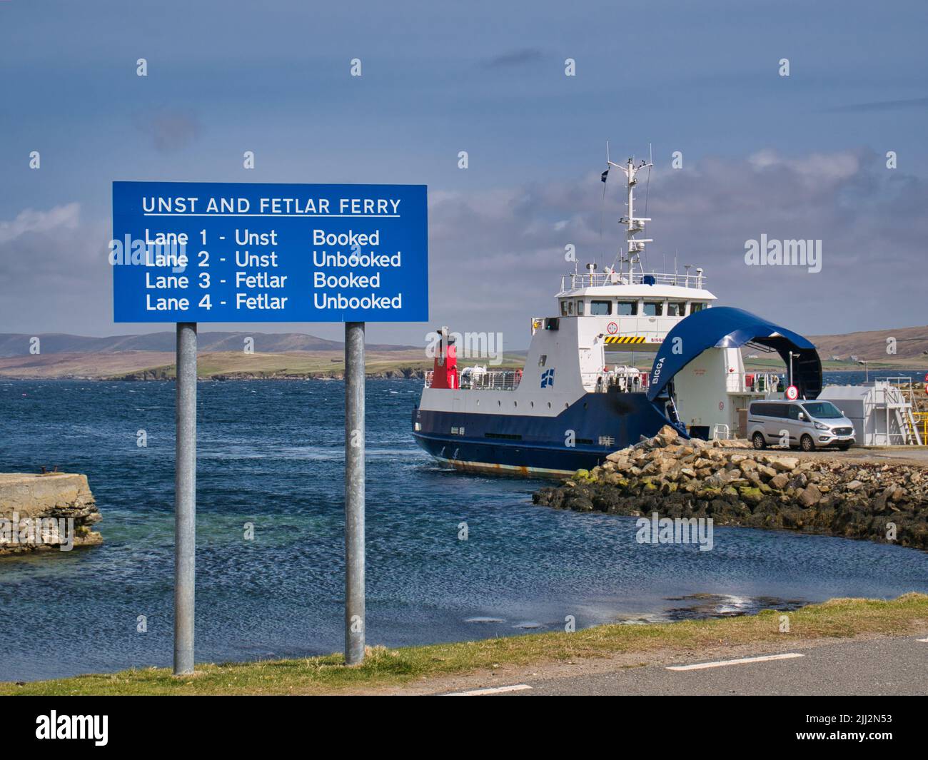 Beschilderung und die Interisland Roll On - Roll Off Fähre MV Bigga am Fährterminal in Gutcher auf der Insel Yell in Shetland, Großbritannien. Stockfoto