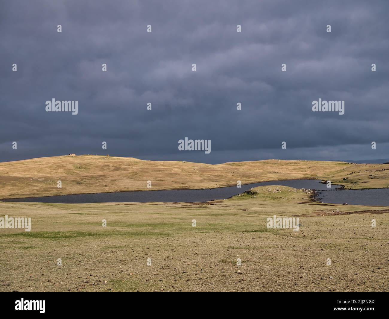 Vor Regen, dunkle Wolken über einer baumlosen Landschaft und lochen (kleiner See) in Eshaness, Shetland, Großbritannien. Stockfoto