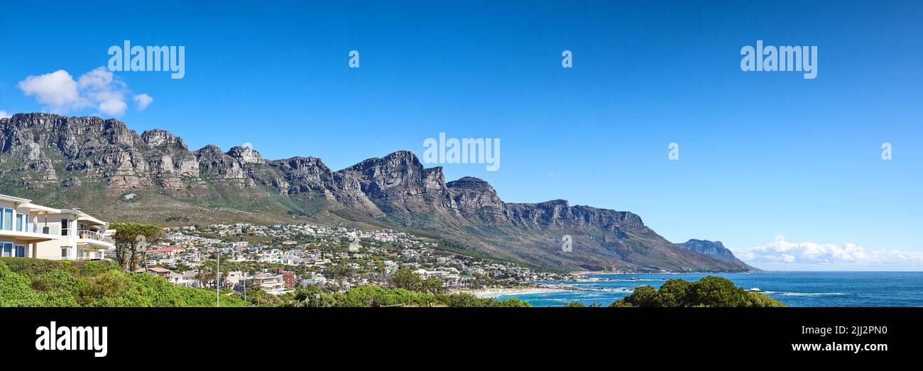 Twelve Apostles am Tafelberg in Kapstadt vor blauem Himmel an der Küste. Atemberaubendes Panorama auf einen ruhigen Vorort umgeben Stockfoto