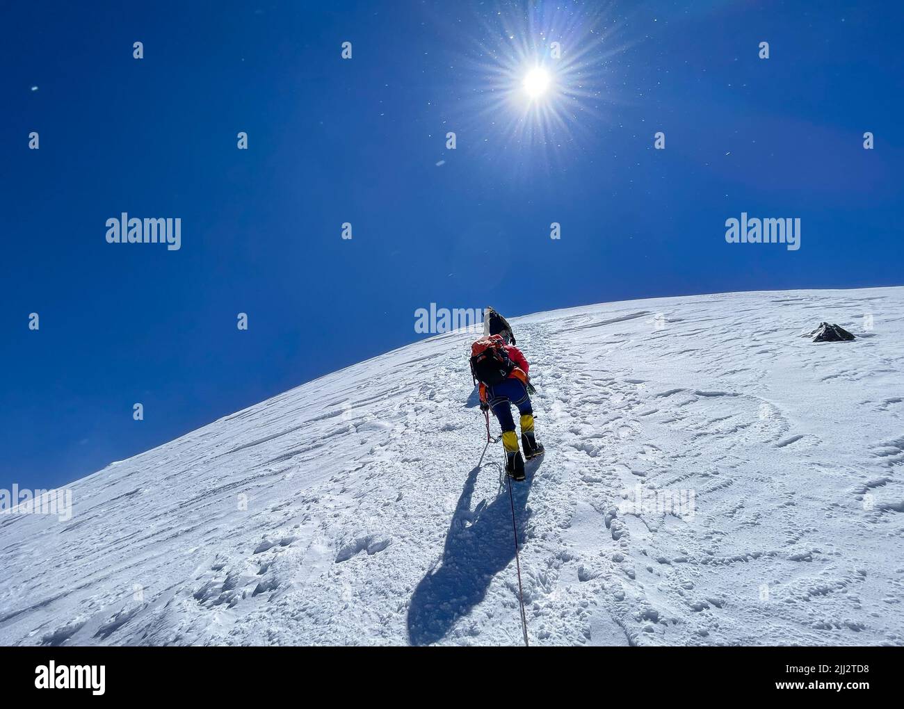 Letzte Schritte vor dem Kazbek (Kazbegi) Gipfel 5054m Seilschaft bekleidet Bergsteigen Kleidung, Stiefel mit Steigeisen aufsteigen durch verschneiten Hang mit blauem Himmel b Stockfoto