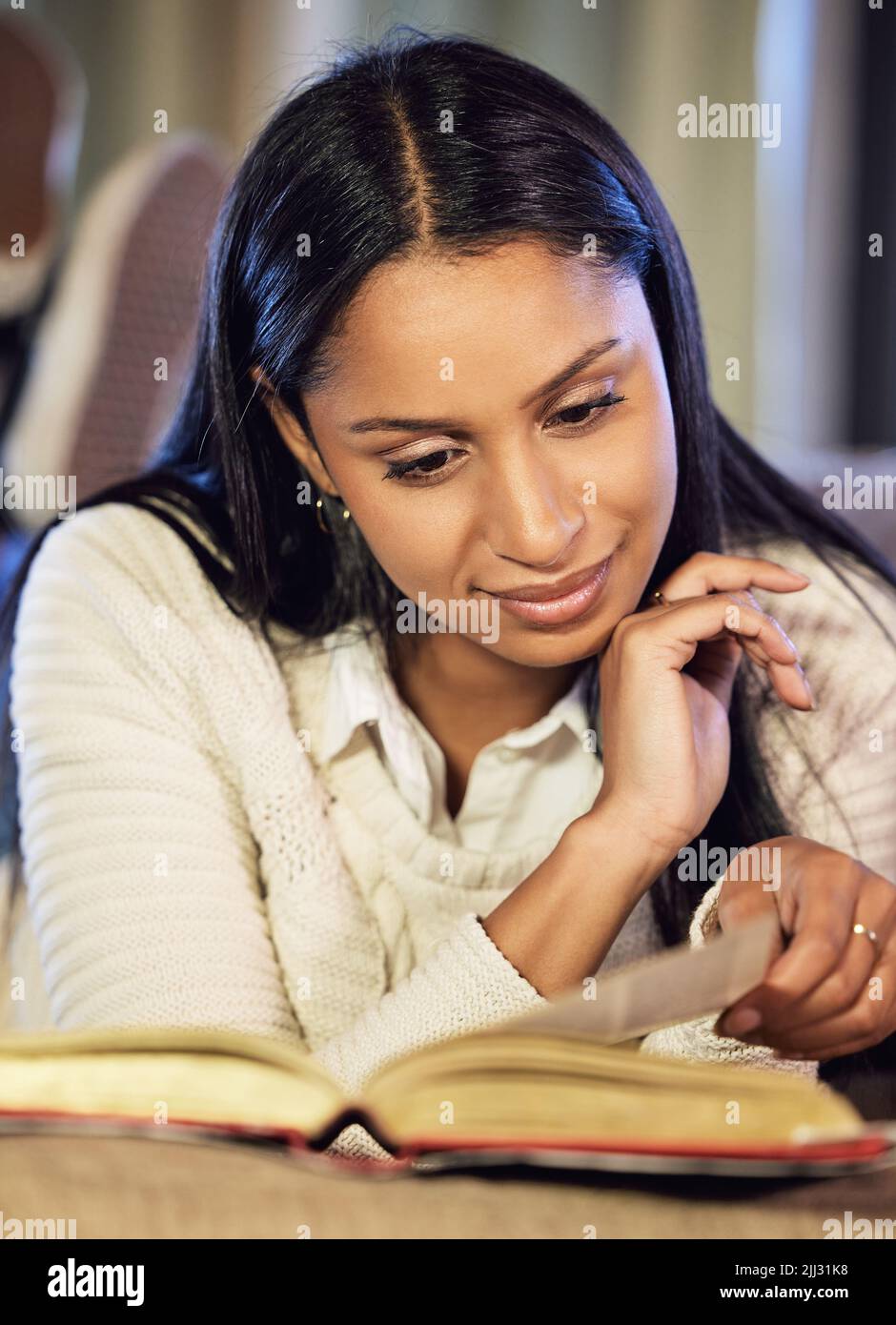 Sich mit dem Studienmaterial vertraut machen. Eine attraktive junge Frau, die zu Hause studiert. Stockfoto