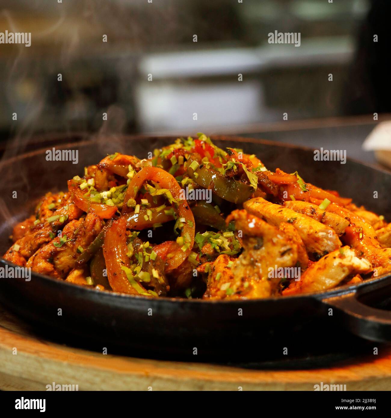 mexikanisches Essen, Hühnerfajitas auf einem heißen, rauchenden, brutzelnden Teller in Nahaufnahme Stockfoto