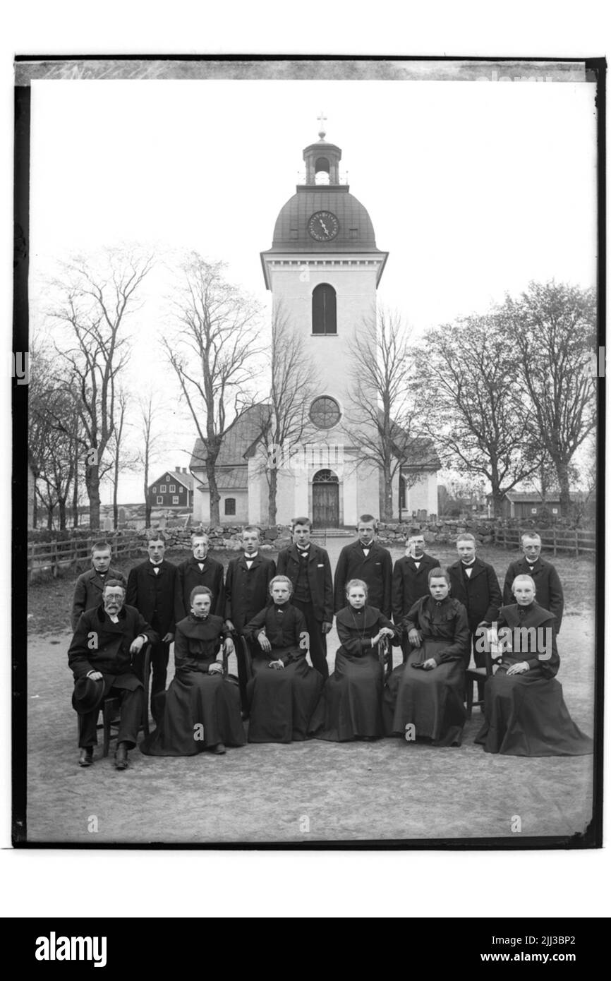 Rinkaby Kirche im Hintergrund. Konfirmen, 14 junge Menschen und Priesterhäuser. Stockfoto