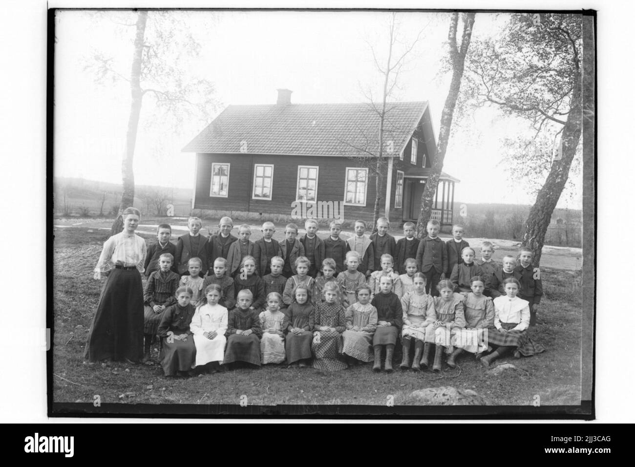 Rinkaby Schule, 39 Schüler und Lehrerin Miss Hanna Gustafsson. Schulgebäude im Hintergrund. Stockfoto